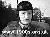 A man from the AA (Automobile Association) in the 1940s or 1950s 
    showing his uniform and helmet.