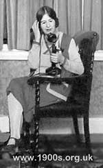 Woman using a candlestick phone sometime in the 1920s 