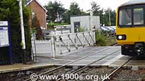 1940s and 1950s style level crossing closed for road traffic and open for trains, thumbnail