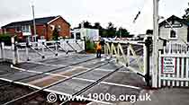 1940s and 1950s style level crossing being opened by a railway worker to allow road traffic to pass, but to close off for trains, thumbnail