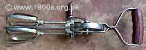 Old hand-operated egg beater, made of metal but with wooden handles